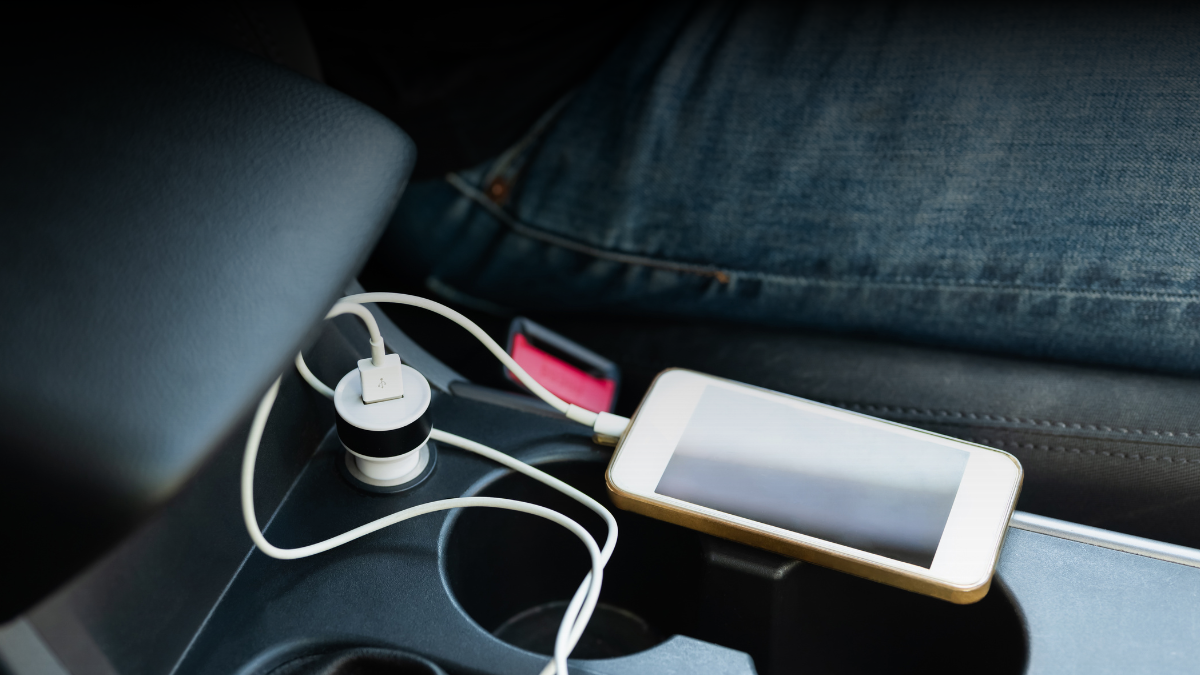 Móvil cargándose en el coche mediante cargador USB conectado al mechero.